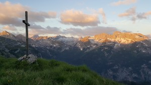 Gipfelkreuz, im Hintergrund erste Sonnenstrahlen auf dem Funtenseetauern und anderen Gipfeln des Steinernen Meeres